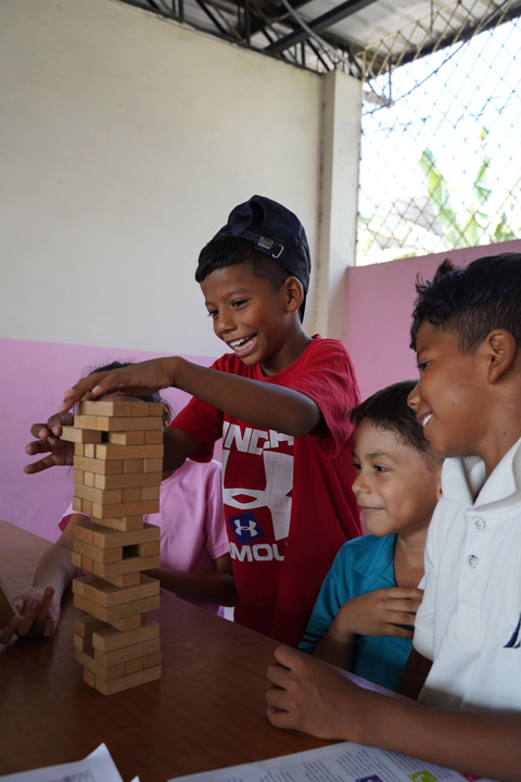 boy building block tower with two other boys