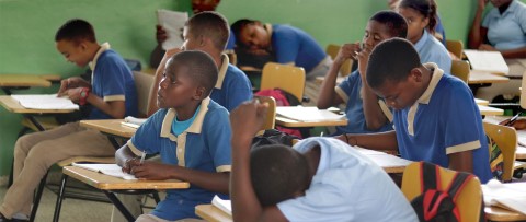un grupo de niños sentados en escritorios en un salón de clases