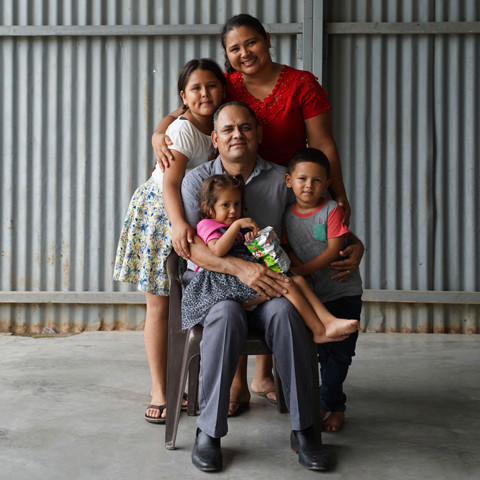 family of five grouped together with man in center holding young girl