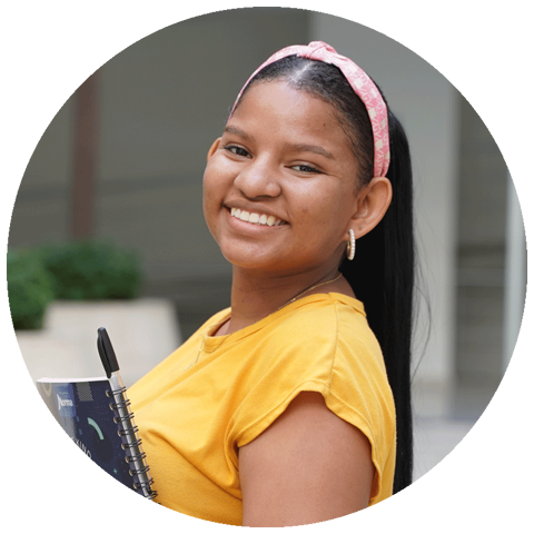 young adult aged girl wearing yellow and holding notebooks smiling at the camera