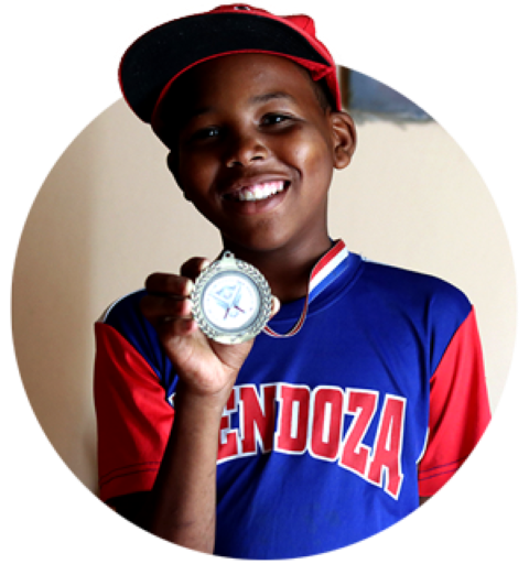 a boy with a medal in his hand smiling at the camera