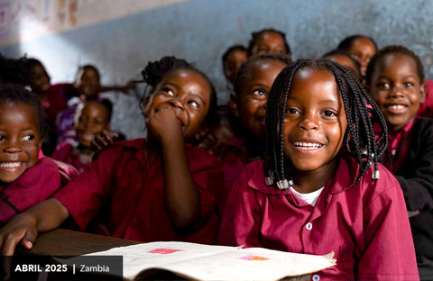 una niña sonríe en su escritorio