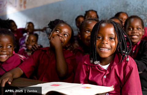 a girl sits at her school desk smiling