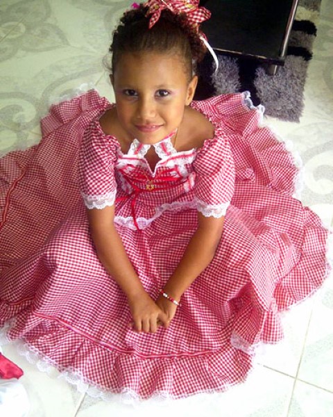 a girl in a typical costume sitting on the floor smiling at the camera