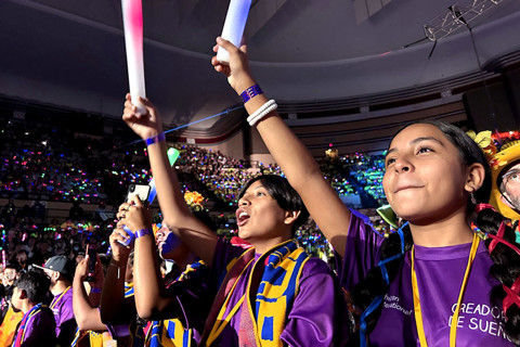 jóvenes con ropa de colores vivos animando en un pabellón abarrotado