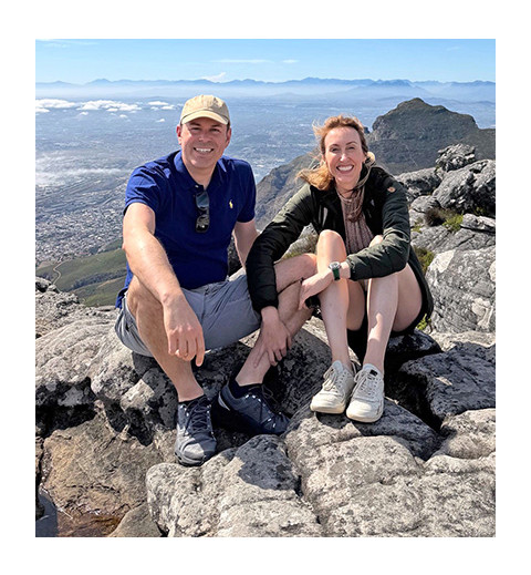 man and woman couple sitting on rocks in front of ocean