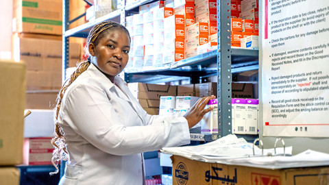 woman in white coat stocking medicines in a clinic