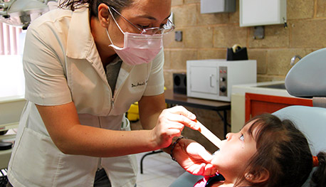Una niña a la que un dentista le revisa los dientes
