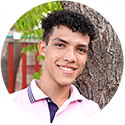 a young man standing next to a tree