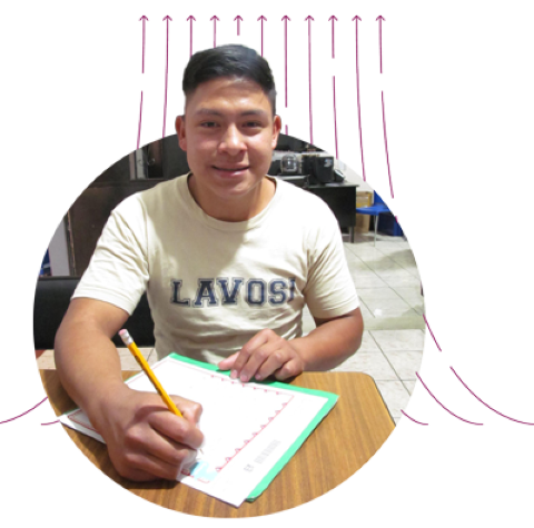 a young boy smiling while writes a letter