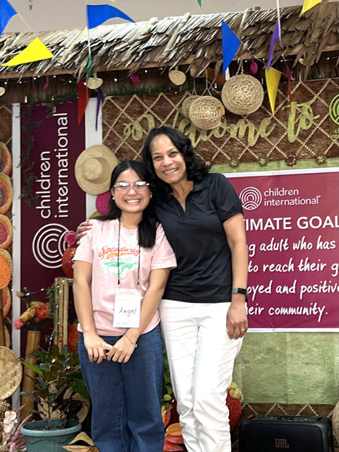 photo of woman smiling with her arm around the shoulder of a young adult wearing glasses