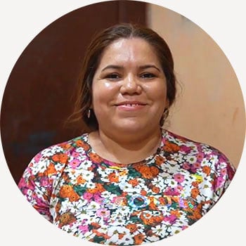 a woman in a floral shirt smiling at the camera